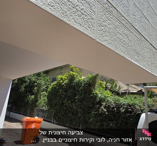 קיר חיצוני עם מרקם, פח כתום וחצר מרוצפת
